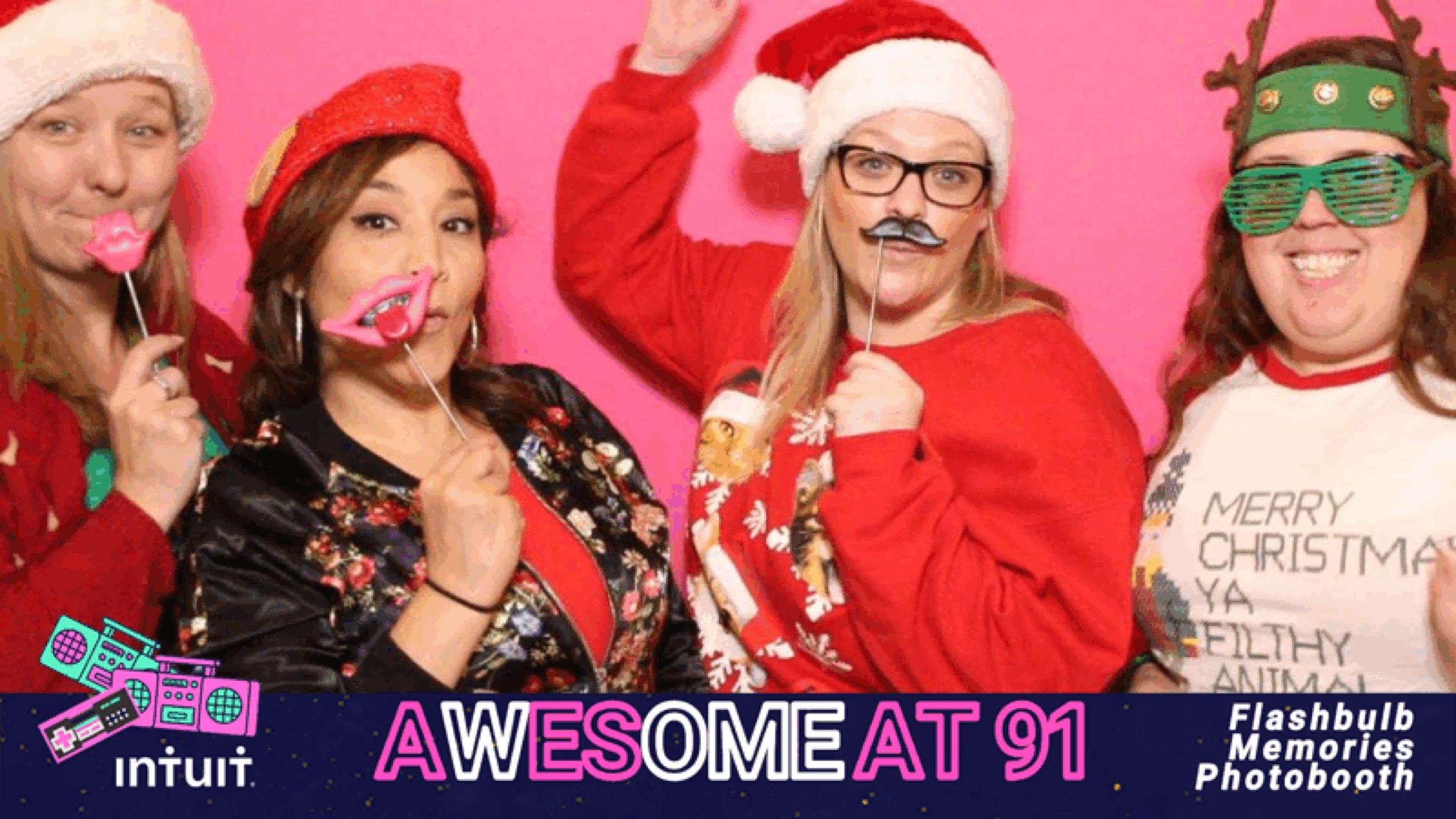 Intuit employees in Santa hats and holiday props posing inside a branded GIF booth frame at the Tucson site party