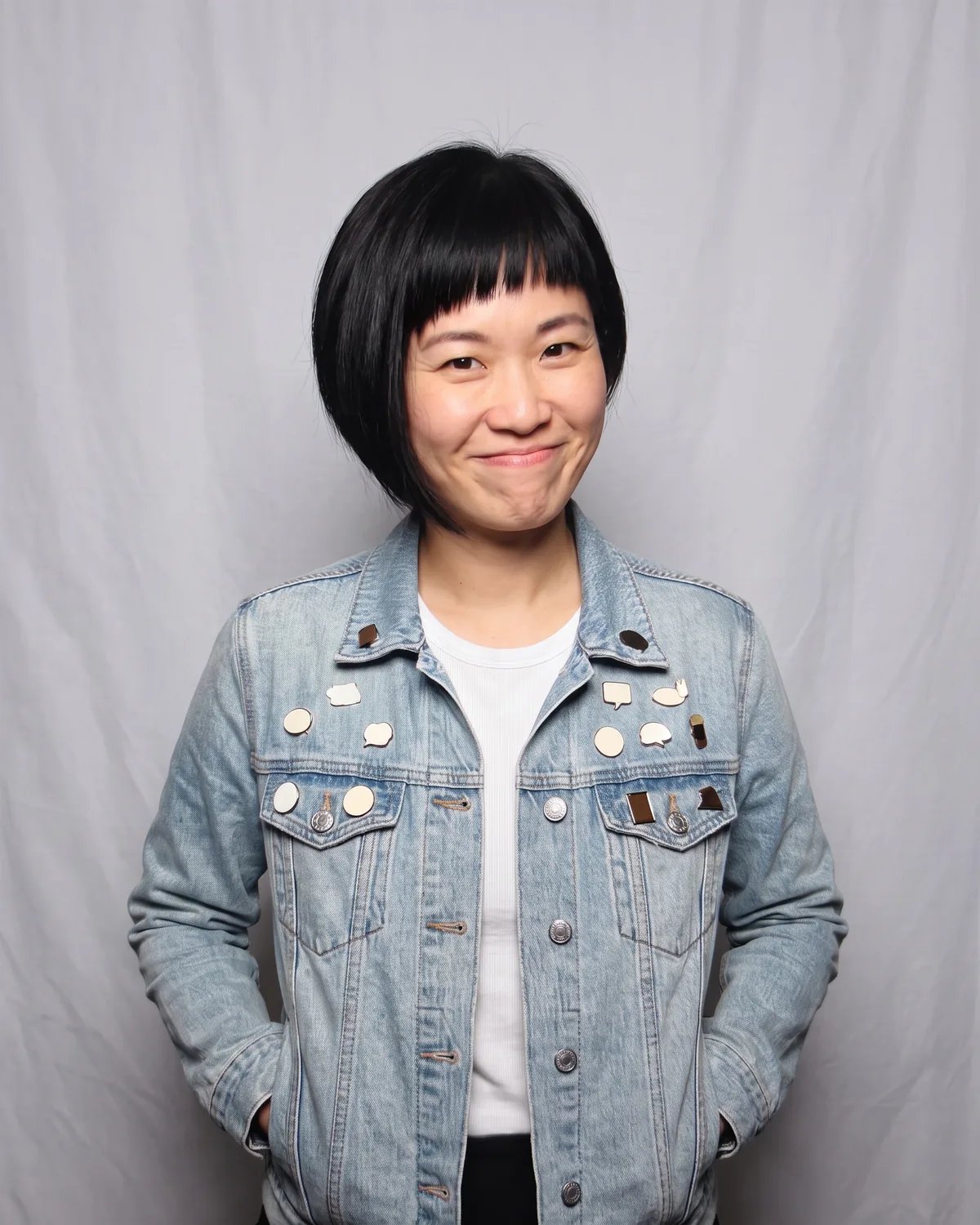 Guest at a tech conference in a denim jacket covered in pins, hands in her pockets