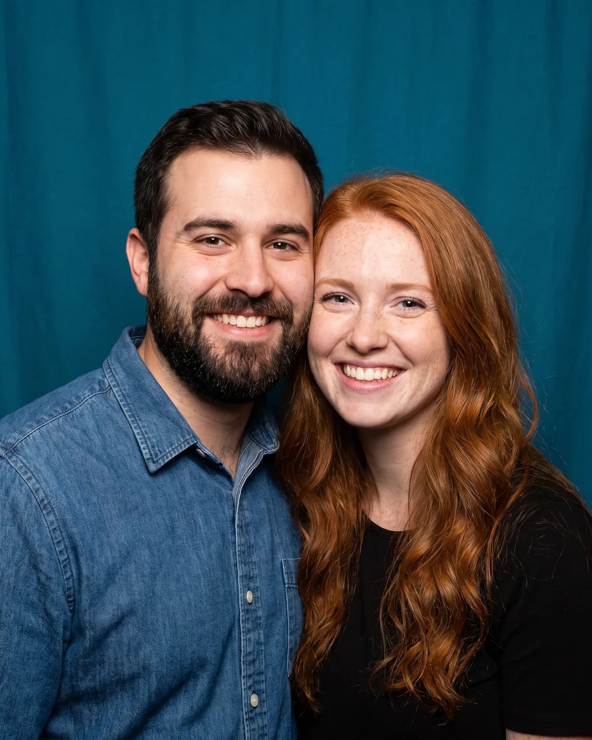 A bearded man and a red-haired woman cheek to cheek at a birthday party