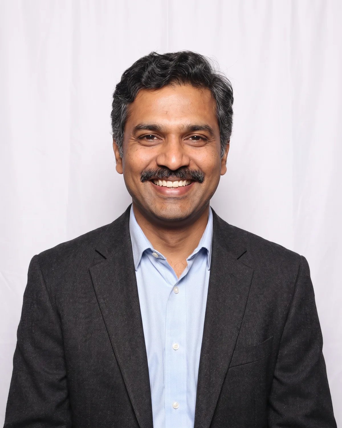 Guest at a company holiday party with a mustache, in a charcoal blazer