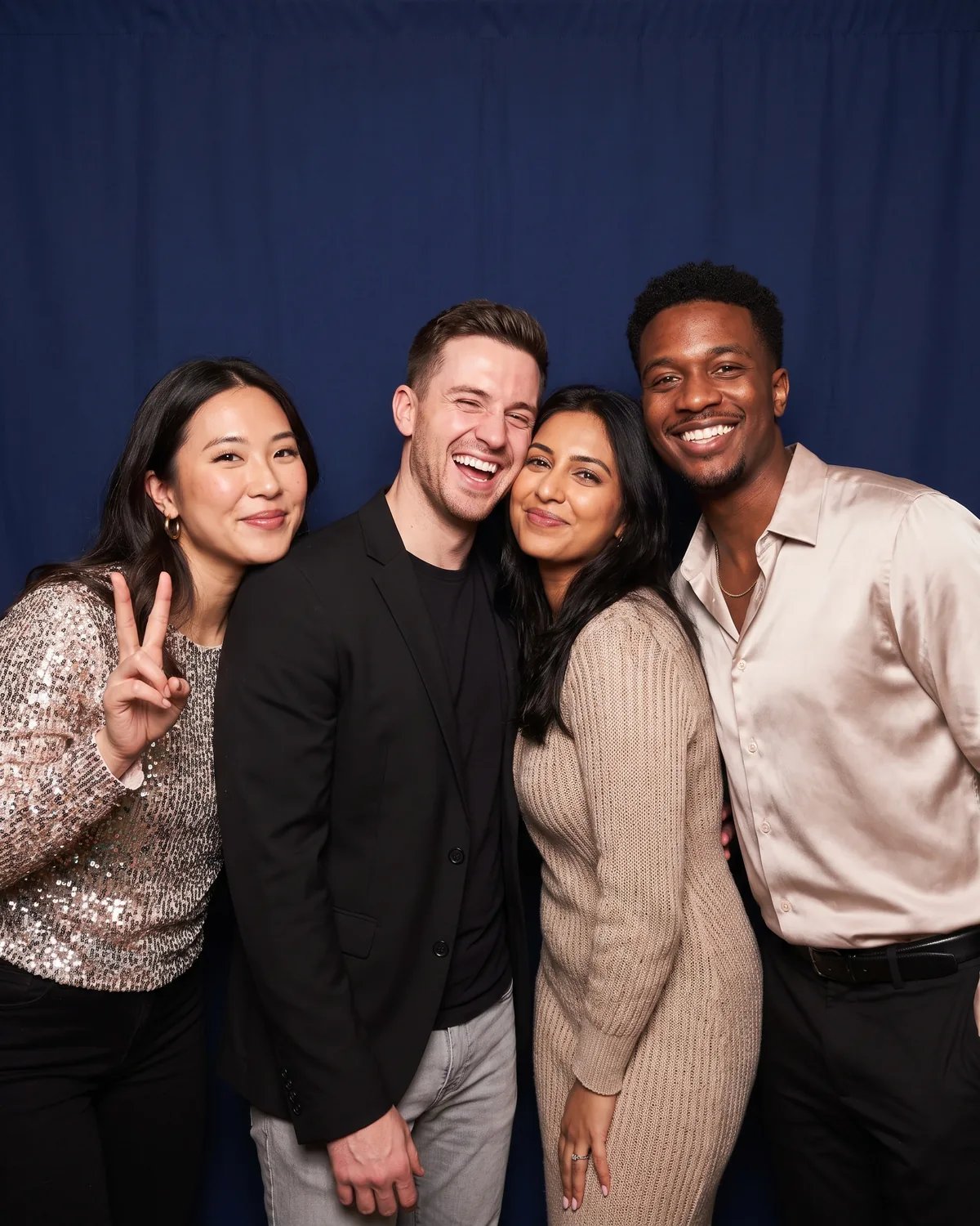Four friends squeezed together at a 30th birthday party, one making a peace sign