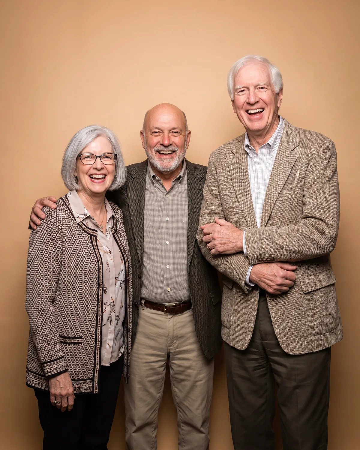 Three coworkers in their sixties laughing with their arms linked