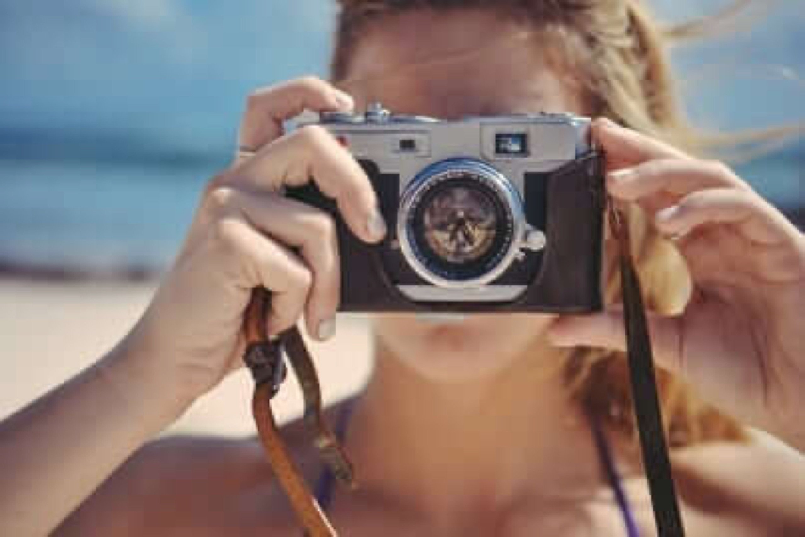 Photographer framing a shot through a manual camera, dialing in settings before the shutter fires