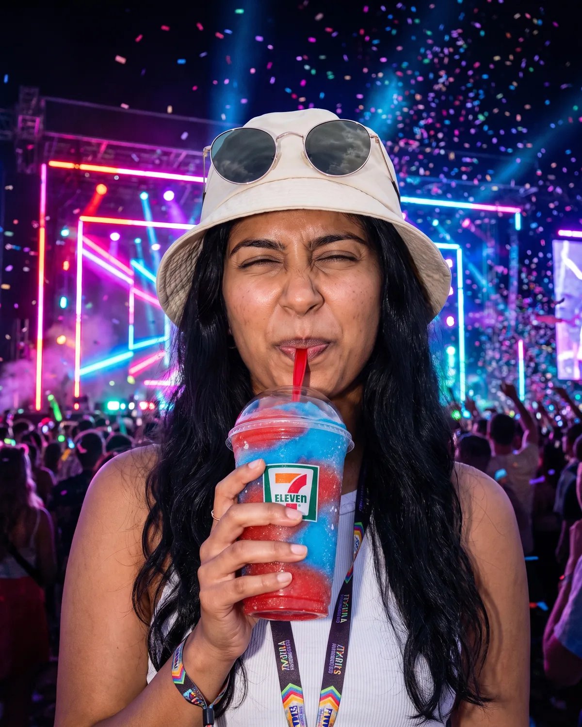 The guest sipping a 7-Eleven frozen drink under neon festival stage lights