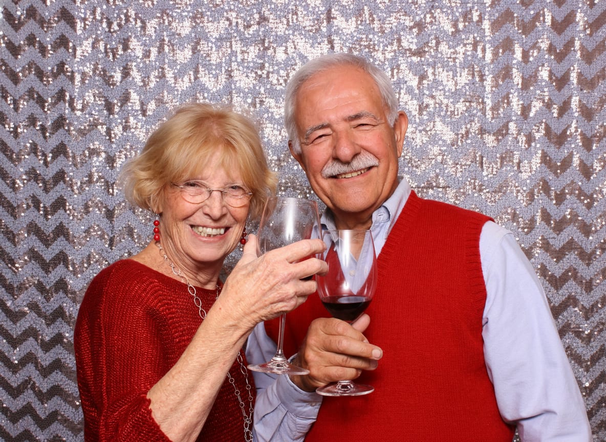 Two guests raising a glass in front of a rose gold chevron sequin backdrop