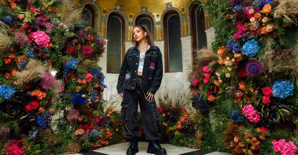 Editorial portrait framed by dramatic floral installations in a grand venue