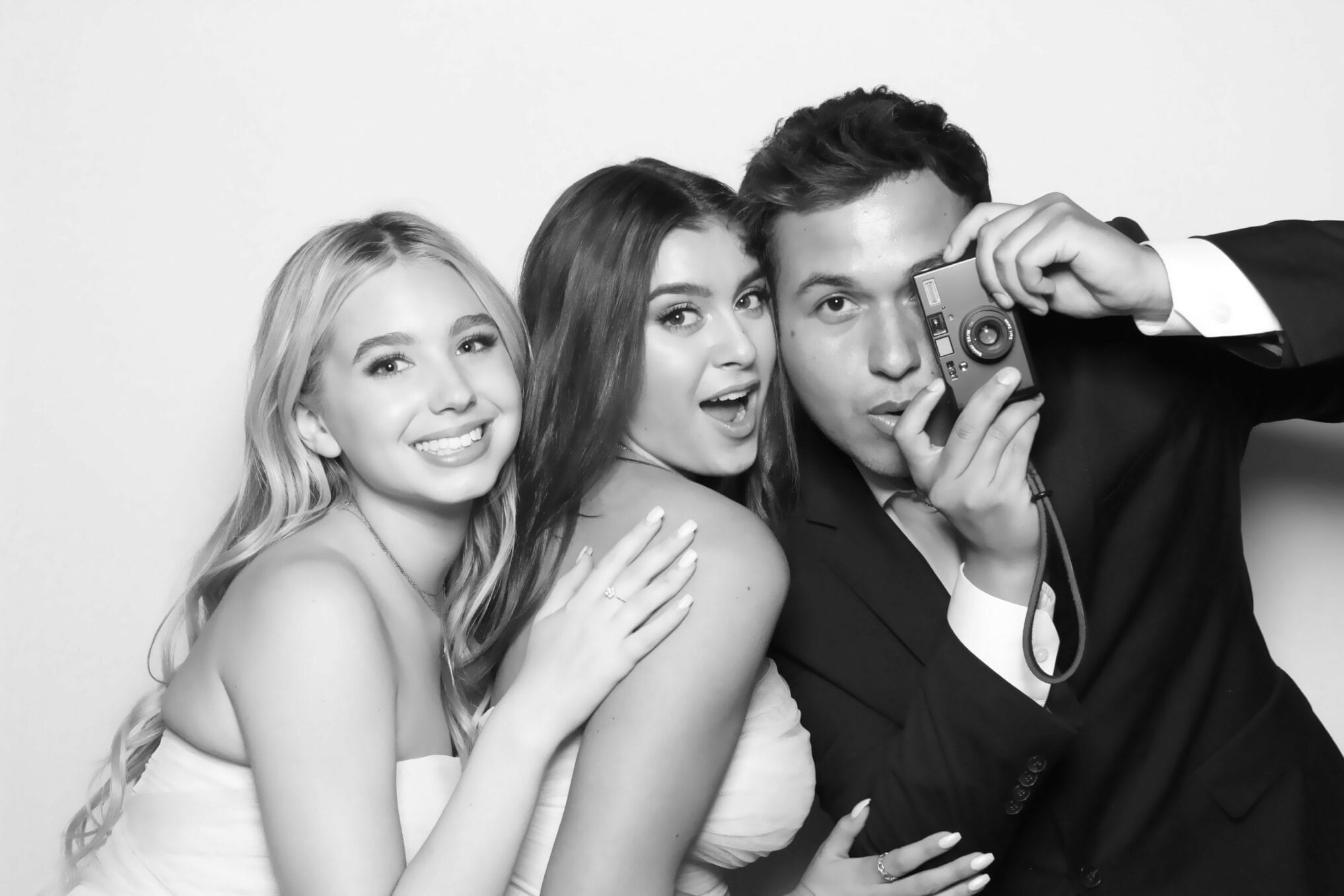 Three guests crowding the frame, one holding a film camera
