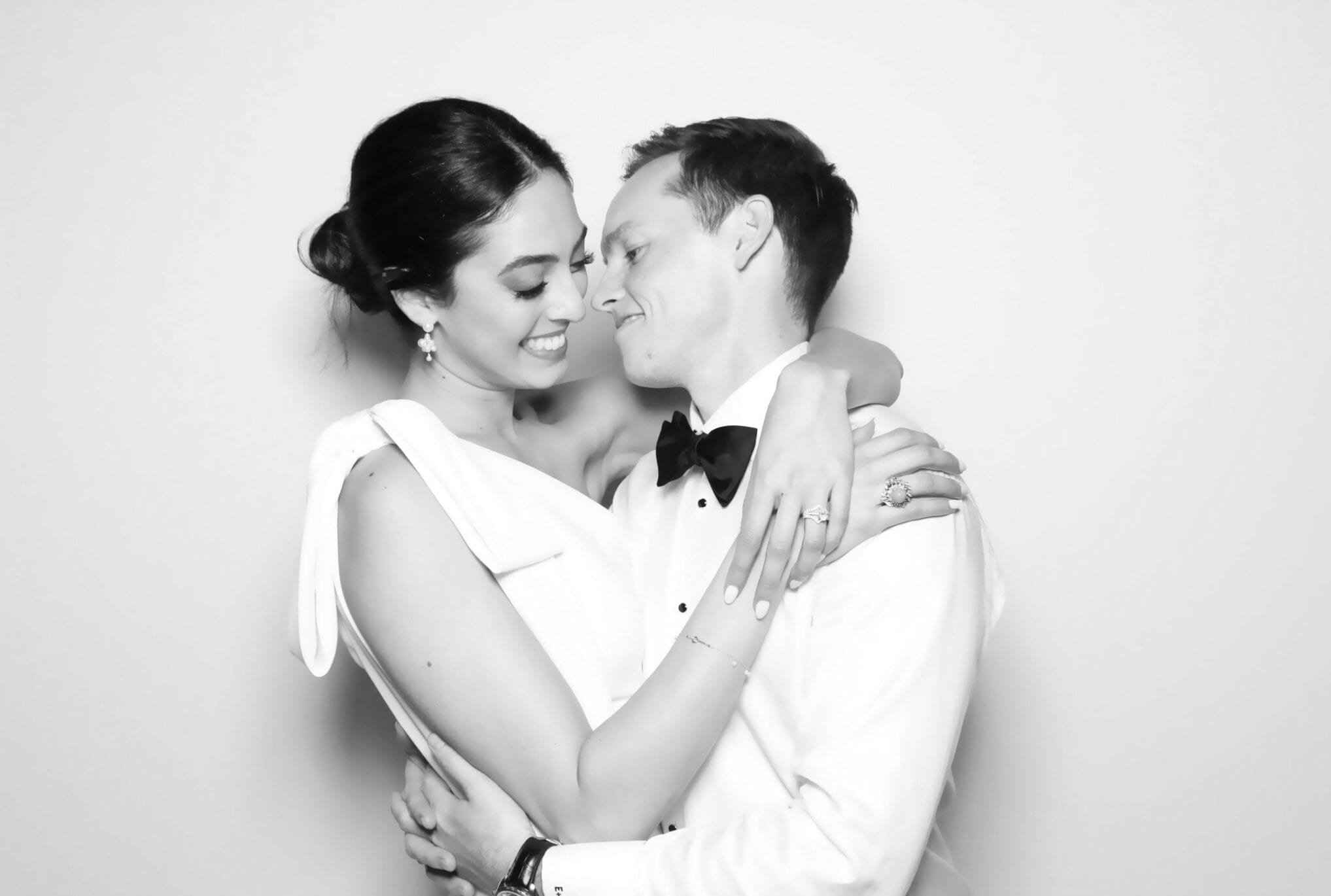 A bride and groom holding each other close in soft glam lighting
