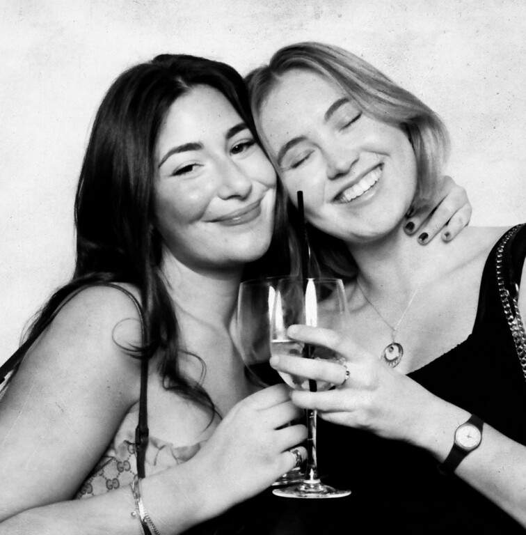 Two friends cheek to cheek with champagne in a Booth by Bryant style vintage booth portrait