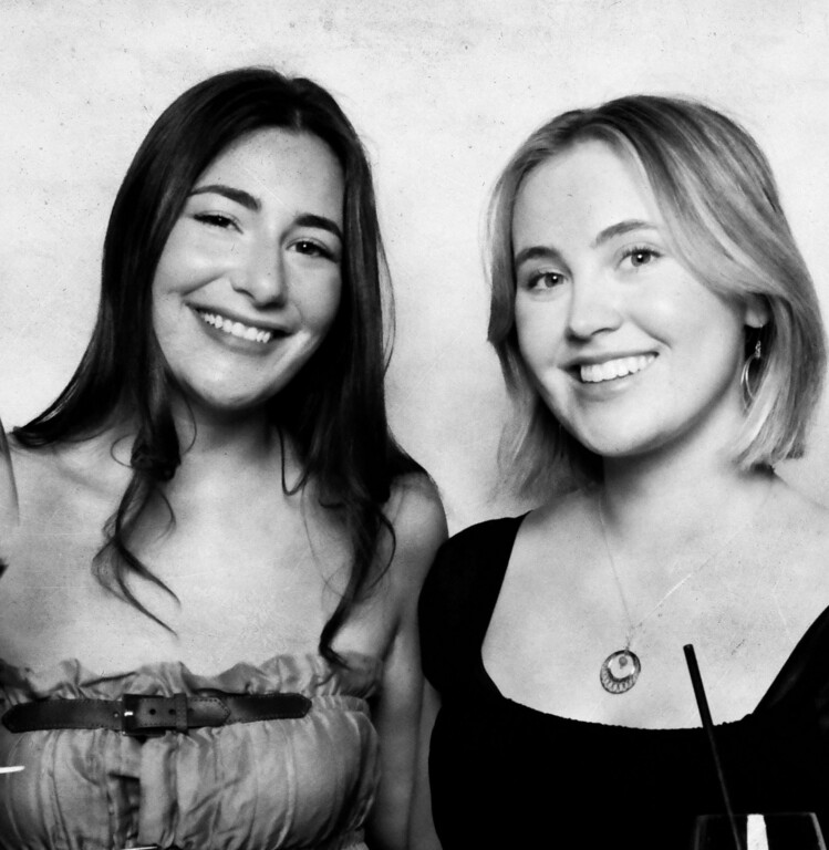 Two friends smiling side by side in a black and white vintage booth portrait